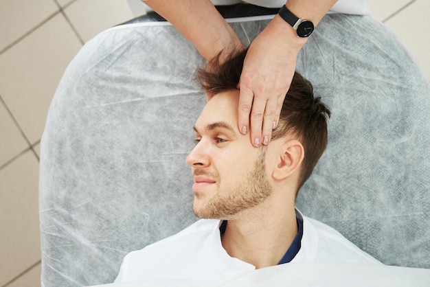 Bonito homem caucasiano tem massagem facial no escritório do cosmetologista closeup Procedimentos de beleza masculinos esteticista rosto cuidados com a pele