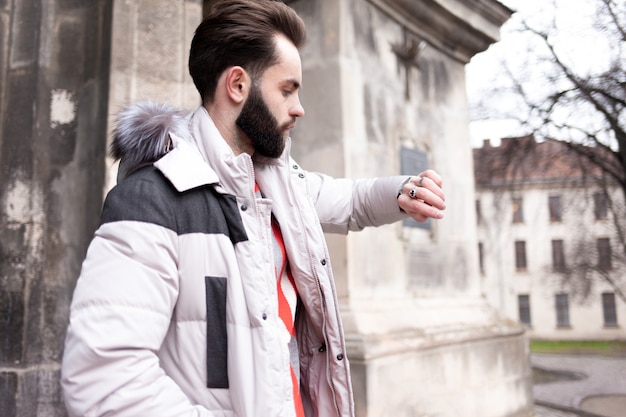 Bonito homem com barba olha para o relógio