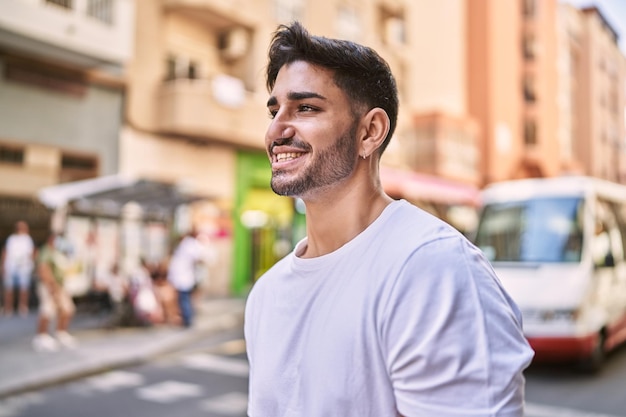 Bonito homem hispânico sorrindo feliz ao ar livre