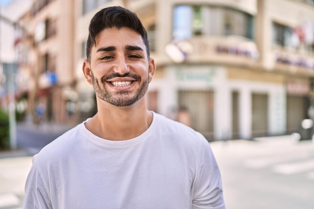 Bonito homem hispânico sorrindo feliz ao ar livre