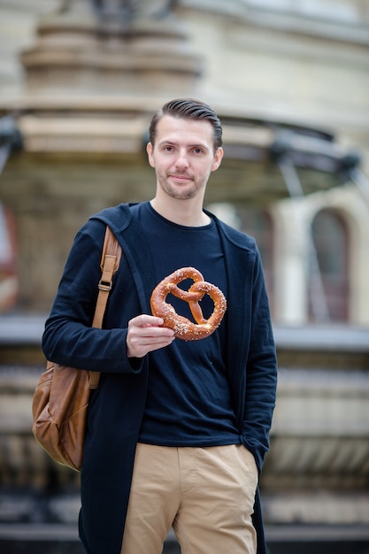 Bonito, homem jovem, segurando, pretzel, e, relaxante, parque