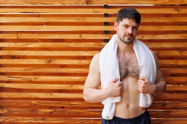 Bonito homem musculoso com um torso nu e uma toalha no pescoço