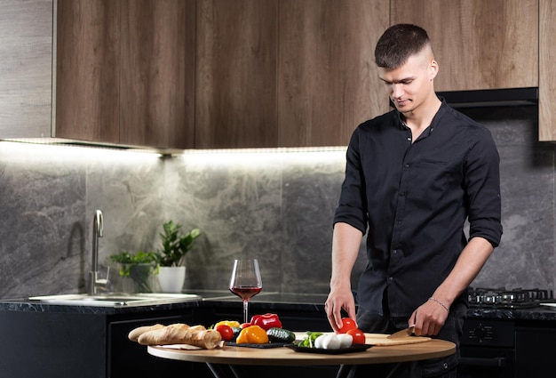 Bonito homem sexy forte na cozinha corta legumes na cozinha Cozinhando