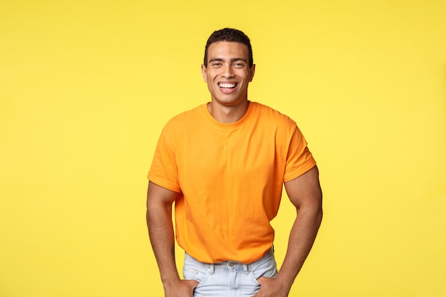 Bonito homem sorridente alegre em camiseta laranja rindo alegremente