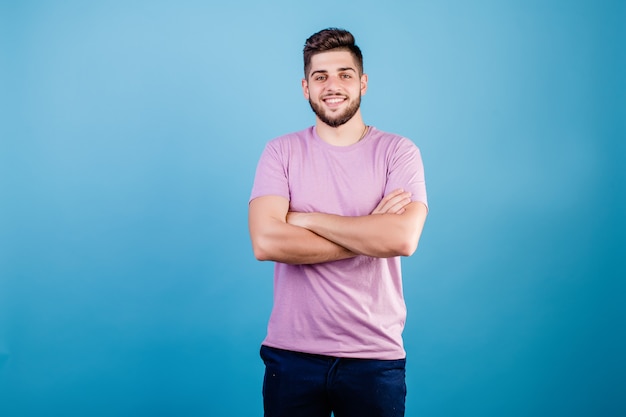 Bonito homem sorridente com as mãos cruzadas no peito isolado no azul