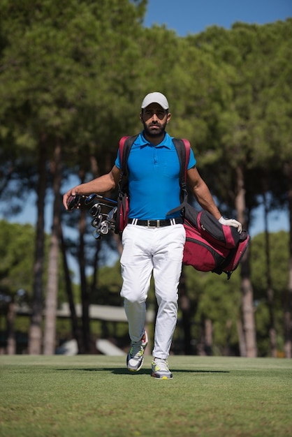 bonito jogador de golfe do oriente médio carregando bolsa e caminhando no curso para o próximo buraco
