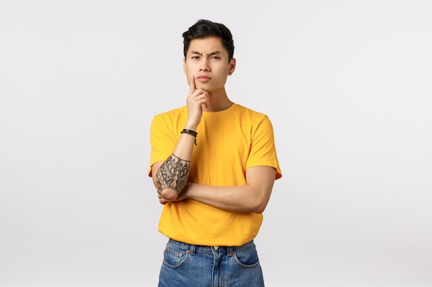 Bonito jovem asiático no pensamento de camiseta amarela