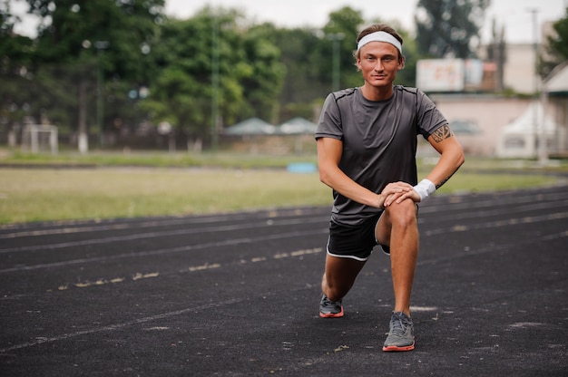 Bonito jovem atleta fazendo exercícios de alongamentos