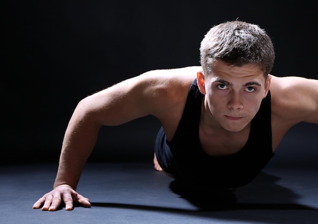 Bonito jovem desportista musculoso em fundo escuro