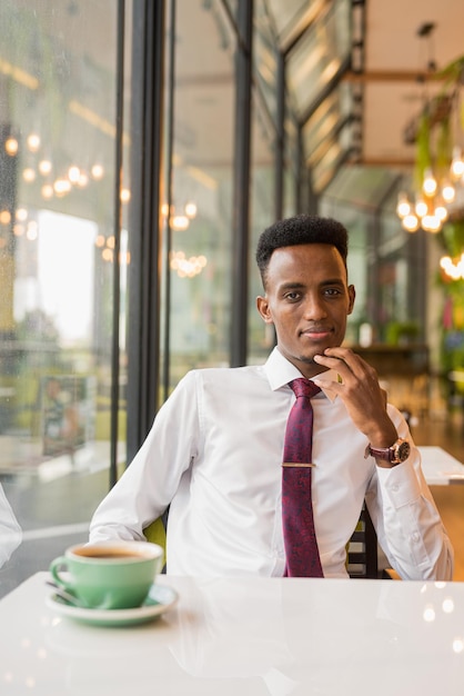 Bonito jovem empresário africano no restaurante de café