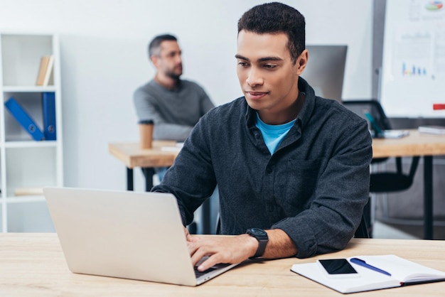 Bonito jovem empresário trabalhando com laptop no escritório