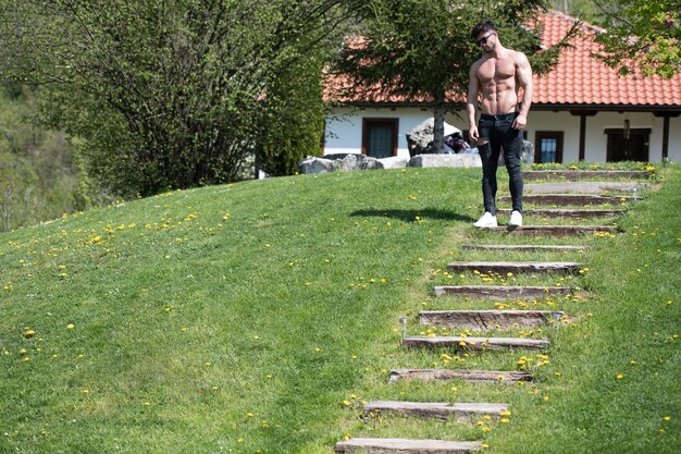 Bonito jovem modelo em pé forte ao ar livre e flexionando os músculos musculoso atleta fisiculturista homem posando um lugar para o seu texto