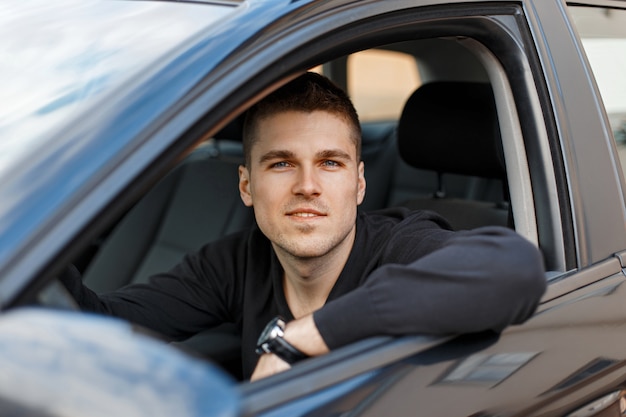 Bonito jovem motorista do sexo masculino em um carro preto