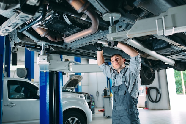 Bonito mecânico de uniforme trabalhando em serviço automotivo