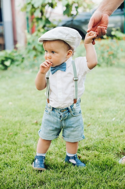 Bonito niño caucásico con ropa elegante camina al jardín con los padres