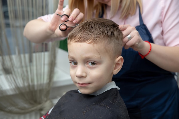 Bonito niño europeo que se peina en la barbería