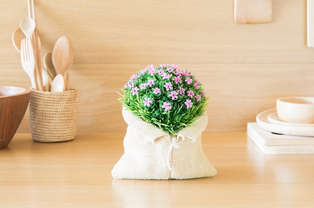 Bonito ramo de flores de plástico en la cocina de madera.