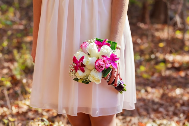 Un bonito ramo de novia de color púrpura, rosa y blanco sostenido por una novia.