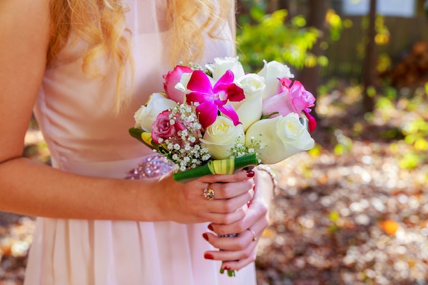 Un bonito ramo de novia de color púrpura, rosa y blanco sostenido por una novia.