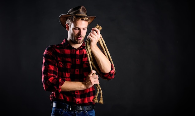 Bonito rancheiro ocidental retrato de vaqueiro ocidental rodeio homem de chapéu fundo preto vaqueiro com corda de laço Homem ocidental camisa quadriculada no rancho Homem estilo vintage vaqueiro retrô do oeste selvagem