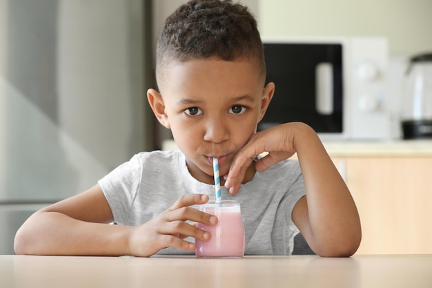 Bonito rapaz afro-americano bebendo iogurte em casa