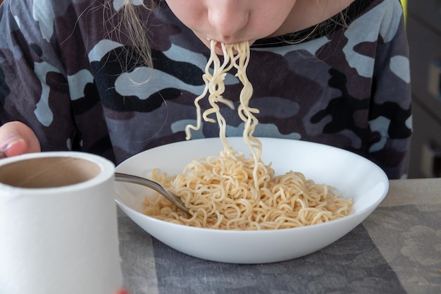 Foto bonito rapaz feliz comendo espaguete na cozinha