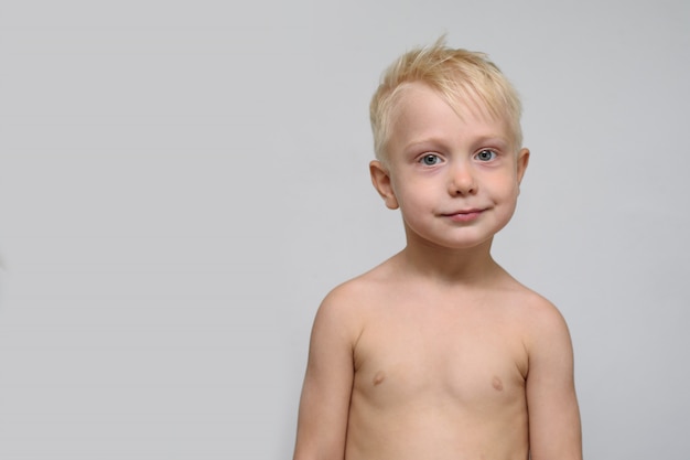 Foto bonito rapaz loiro sorridente sem camisa. retrato. espaço para texto. branco