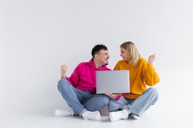 Bonito retrato de pareja con portátil sentado fondo gris