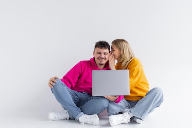 Bonito retrato de pareja con portátil sentado fondo gris