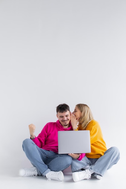 Bonito retrato de pareja con portátil sentado fondo gris