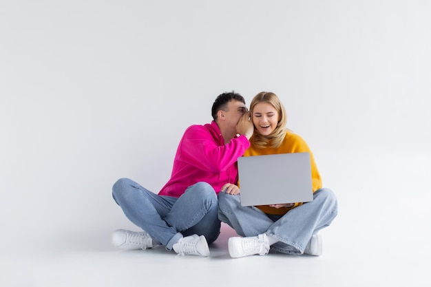 Bonito retrato de pareja con portátil sentado fondo gris