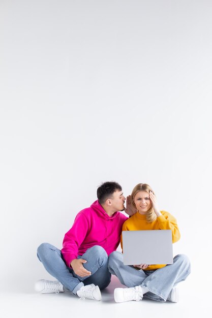 Bonito retrato de pareja con portátil sentado fondo gris