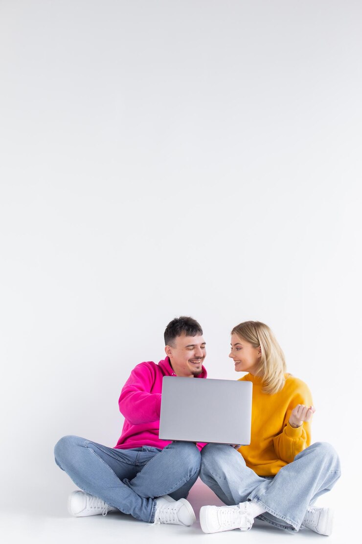 Bonito retrato de pareja con portátil sentado fondo gris