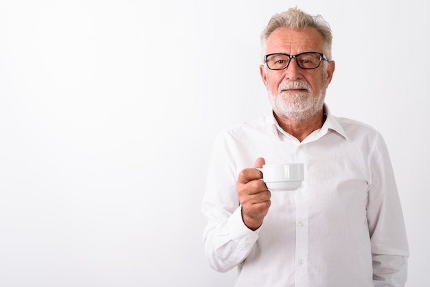 Foto bonito sênior barbudo segurando uma xícara de café com óculos em branco