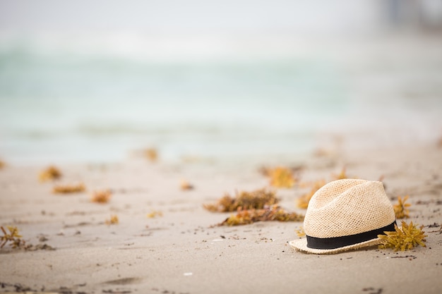 Bonito sombrero de paja tumbado en la arena de la playa del océano