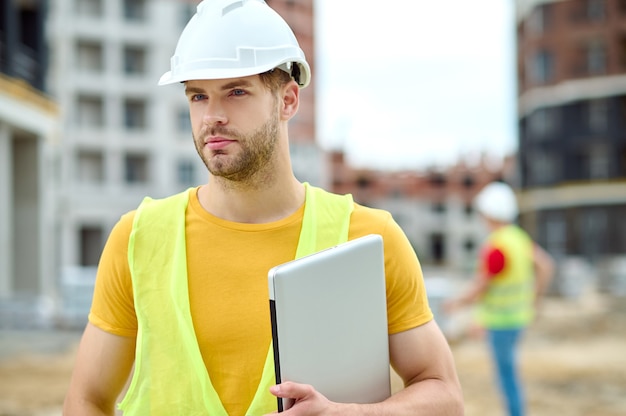 Bonito trabalhador da construção civil focado em chapéus, olhando para o futuro