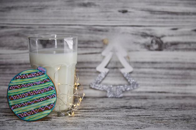 Bonito tradição de Natal Biscoitos frescos artesanais e vidro com leite para o Papai Noel na mesa de madeira vintage Clima festivo de Natal e atmosfera estética com fundo de guirlandas Espaço de cópia