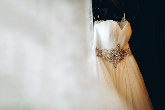 Bonito vestido de novia blanco colgado en la habitación de la novia.