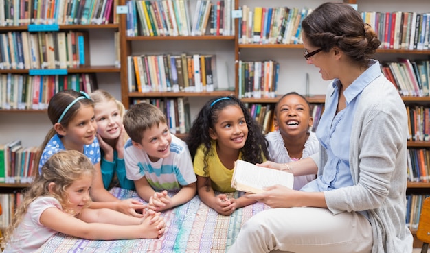 Foto bonitos alunos e professor lendo na biblioteca