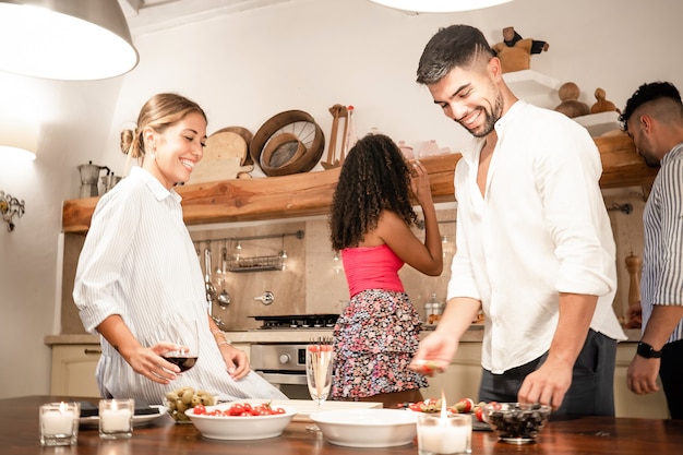 Bonitos amigos da geração Y se juntam em casa preparando lanches para aperitivos