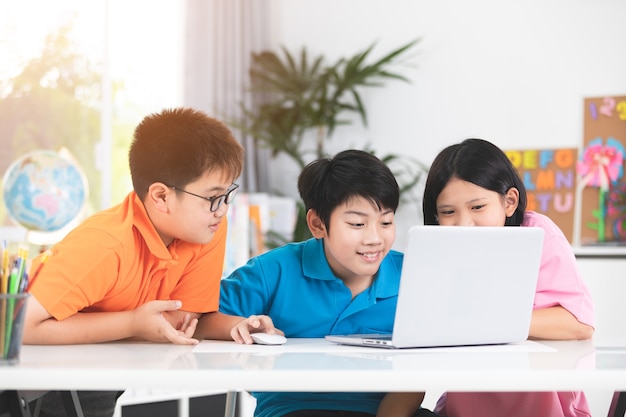 Bonitos crianças asiáticas usando laptop juntos.