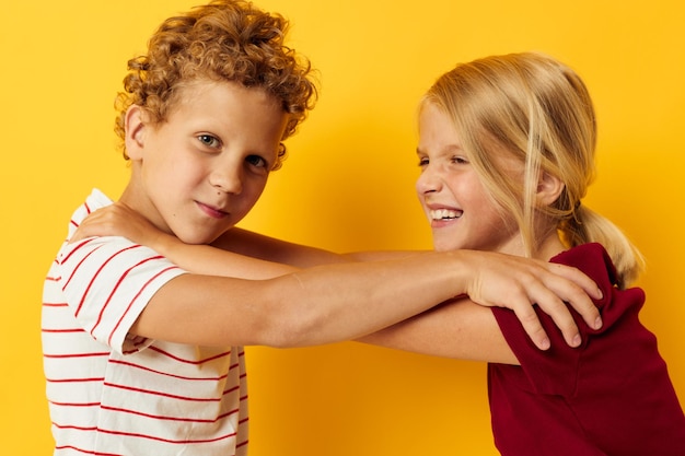 Bonitos crianças pré-escolares abraçando moda entretenimento infantil fundo amarelo