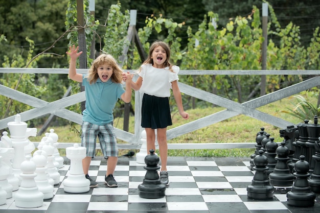 Bonitos criancinhas brincando no grande retrato de tabuleiro de xadrez de duas crianças felizes no parque primavera