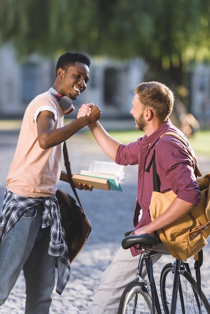 Bonitos estudantes multiétnicas cumprimentando no parque