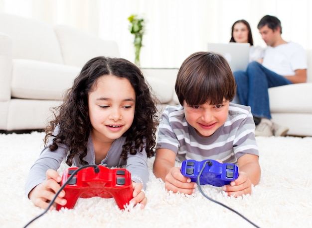 Foto bonitos irmãos jogando videogames deitados no chão