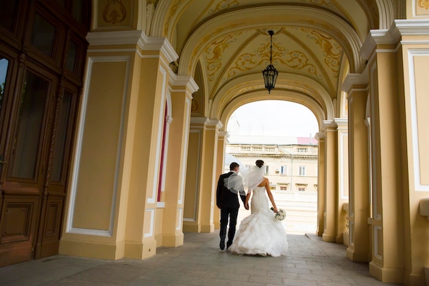 Bonitos recién casados caminan bajo los arcos de la iglesia.