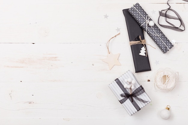 Bonitos regalos de Navidad embalados en papel negro y rayado y decorados con estrellas sobre fondo de madera