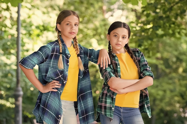 Foto bons alunos roupa de descolados casuais retrato de irmãs felizes crianças meninas de camisa duas jovens garotas descoladas sorridentes em roupas da moda de verão crianças despreocupadas posando ao ar livre modelos positivos