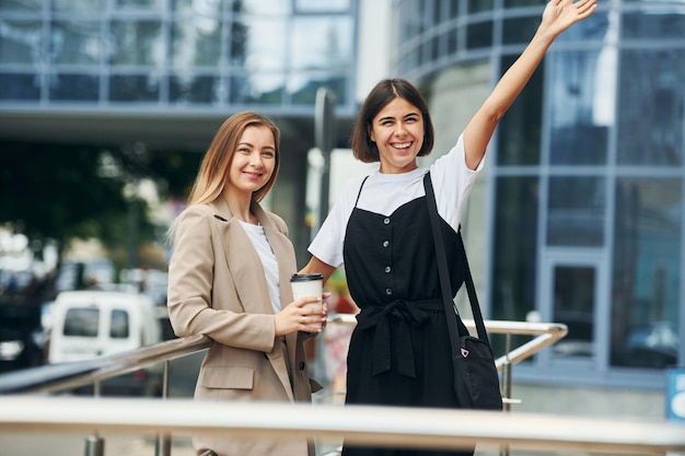 Bons amigos Mulheres com roupas formais estão ao ar livre na cidade juntos