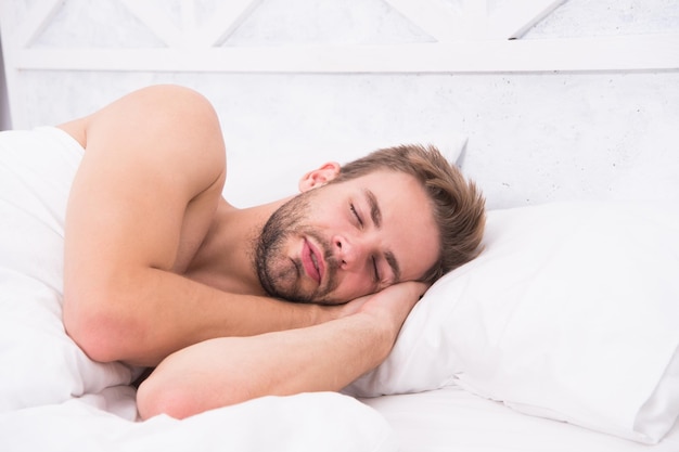 Bons sonhos Conceito de cuidados de saúde O ritmo circadiano regula o ciclo do sono Homem barbudo bonito na cama Quantidade suficiente de sono todas as noites Dicas para dormir melhor Homem barbudo relaxando no travesseiro